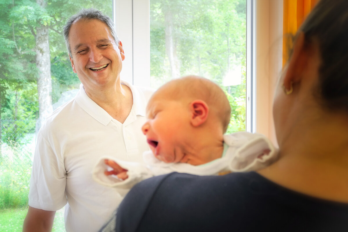 Dr. Winfried Eschholz, Chefarzt der Geburtshilfe das Krankenhauses Füssen, im Gespräch mit einer Mutter, die ihr Baby auf dem Arm hält.