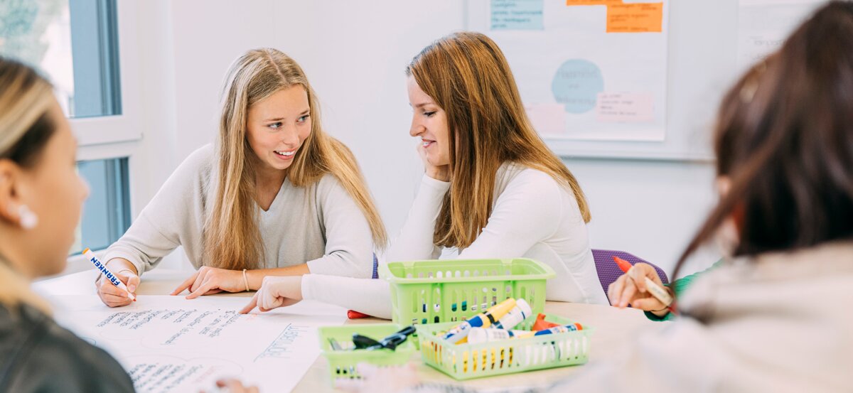 Pflegeschülerinnen sitzen an einem Tisch im Klassenzimmer während der Ausbildung zum Pflegefachhelfer (m/w/d) | © Kliniken Ostallgäu-Kaufbeuren