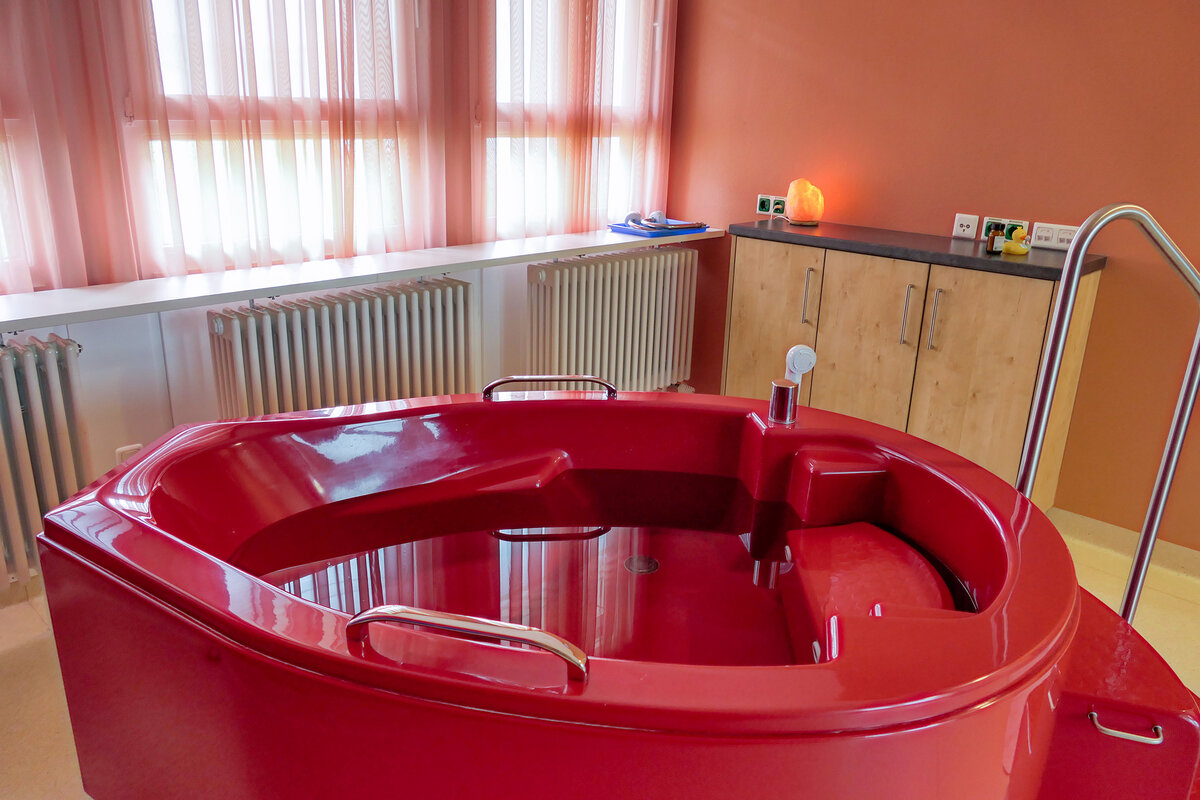 Geburtsraum mit Badewanne zur Wassergeburt und beruhigender Lichtstimmung