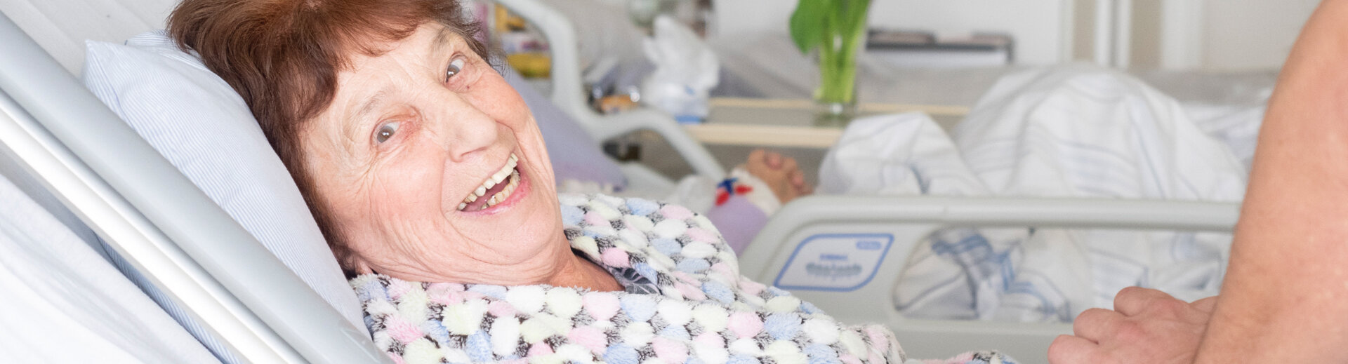 Gut gelaunte ältere Frau im Patientenbett