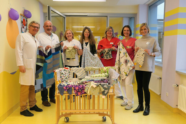 Freuen sich über die individuell genähten Frühchen-Kleidungsstücke (v.l.n.r): Chefarzt Prof. Dr. Markus Rauchenzauner, Leitender Oberarzt der Neonatologie Dr. Jörg Stephanus Franke, aus dem Harl.e.kin-Team Andrea Wierschbitzki und Heike Trick, Kinderkrankenschwestern Kerstin Schuster und Marion Spetlak-Ptascheck und Harl.e.kin-Koordinatorin Sabine Nester | © Kliniken Ostallgäu-Kaufbeuren