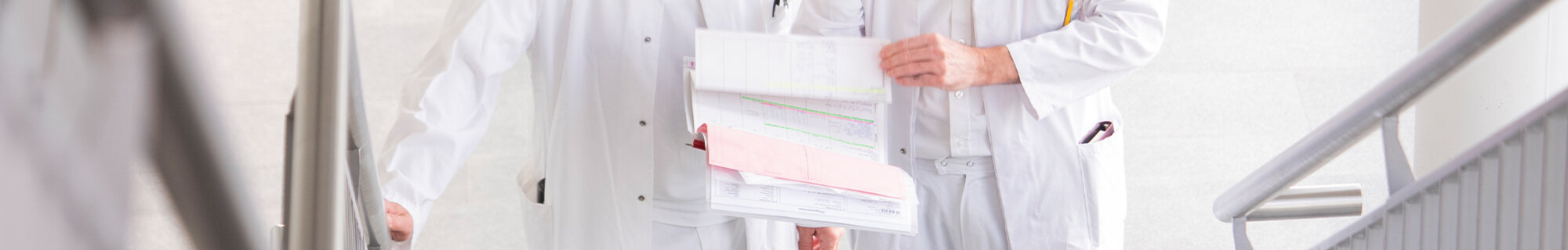 Zwei Ärzte besprechen mögliche Therapien im Anblick einer Patientenakte | © Kliniken Ostallgäu-Kaufbeuren